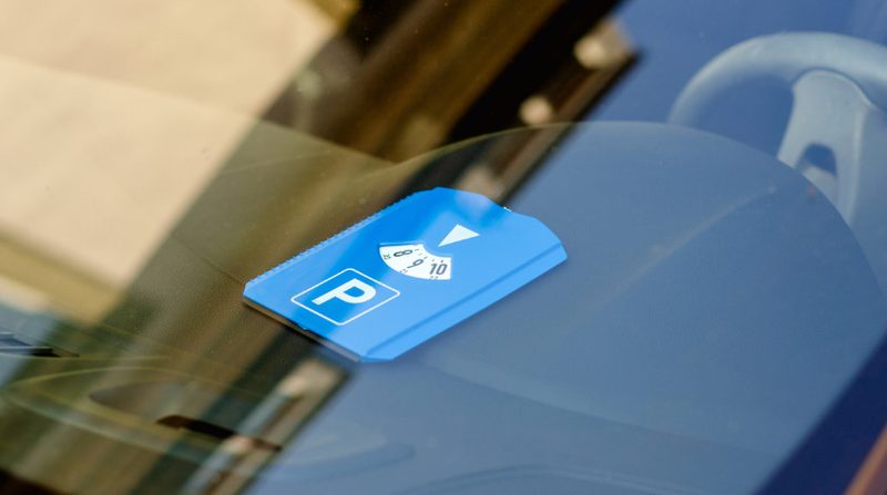 Blaue Parkscheibe hinter der Windschutzscheibe eines Autos